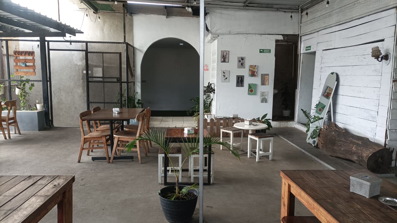 Area duduk Mazalat — papan kayu COFFEE, lantai beton, tanaman hias